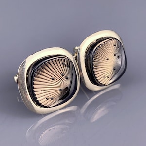 May include: A pair of gold-toned cufflinks with black and gold fan-shaped designs.