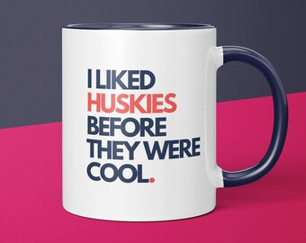 May include: White ceramic mug with a blue rim and handle. The mug has the text "I LIKED HUSKIES BEFORE THEY WERE COOL." printed in blue and red.