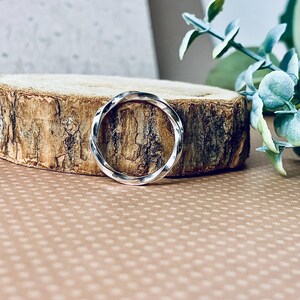 May include: A silver twisted band ring on a wooden surface.