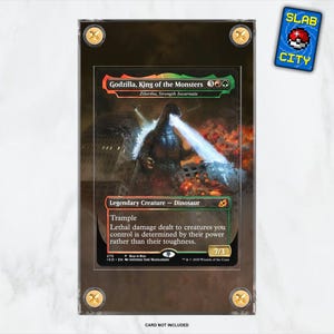 Puede incluir: Una carta de Magic: The Gathering Godzilla, Rey de los Monstruos con un borde verde, rojo y negro y una ilustración de Godzilla. El texto de la carta dice "Criatura legendaria - Dinosaurio, Pisotear, El daño letal infligido a las criaturas que controlas se determina por su poder en lugar de su resistencia. 7/3".