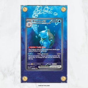 May include: A blue and silver Pokemon card featuring Blastoise EX, a blue turtle-like Pokemon with a large cannon on its back. The card is numbered 330 and has the text "Solid Shell" and "Twin Cannons" on it.