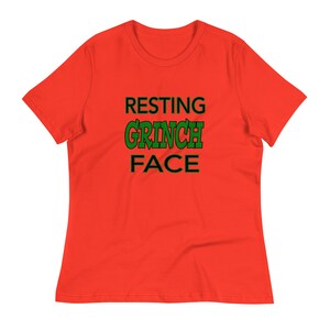 May include: Red t-shirt with the text "RESTING GRINCH FACE" in black and green lettering.