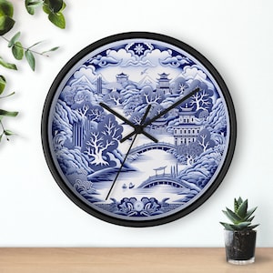 May include: A blue and white porcelain clock with a black frame. The clock face features a traditional Chinese landscape design with bridges, trees, and buildings.