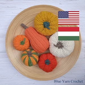Puede incluir: Un plato de madera con siete calabazas de ganchillo en varios colores, incluyendo naranja, amarillo, blanco y verde. Las calabazas están dispuestas en círculo en el plato. El plato está sobre una superficie blanca. Blue Yarn Crochet.