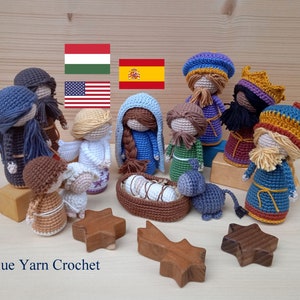 May include: A crocheted nativity scene with figures of Mary, Joseph, baby Jesus, the three wise men, and a shepherd. The figures are all dressed in colorful clothing and have detailed features. The scene is set on a wooden surface with a star and a wooden block.