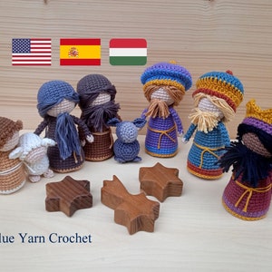 May include: Crocheted nativity scene with figures of the three wise men, Mary, Joseph, and a lamb. The figures are made with colorful yarn and are standing on a wooden surface. The image also includes three wooden stars.