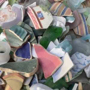 May include: A collection of sea glass and pottery shards in various colors. Pieces include green, blue, pink, and white fragments, some with striped or patterned designs. The image showcases a variety of shapes and textures, suggesting a beachcombing theme.