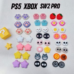 Peut inclure: Ensemble de grips de pouce de joystick colorés de différentes formes, notamment des empreintes de pattes, des étoiles et des personnages de dessins animés. Le texte "PS5 XBOX SW2 PRO" est en haut. Pour manettes de jeu.