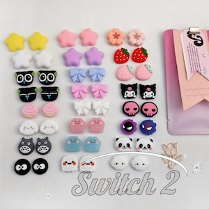 May include: A collection of colorful, decorative charms in various shapes, including stars, flowers, bows, strawberries, skulls, and cartoon characters. The charms are in shades of yellow, pink, purple, blue, red, black, and white. The text "Switch 2" is at the bottom.