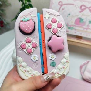 Close up of pink star thumb grips and strawberry caps for Switch 2 cozy gamer setup.