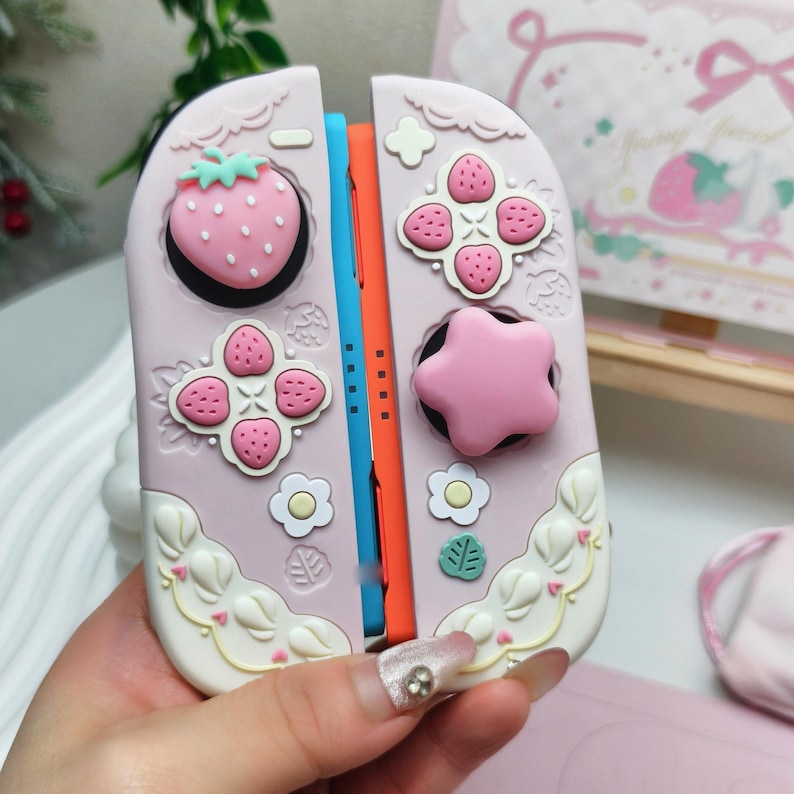 Close up of pink star thumb grips and strawberry caps for Switch 2 cozy gamer setup.