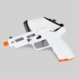 Puede incluir: Una pistola de airsoft blanca y negra con punta naranja. La pistola tiene el texto "TACTSIM" y "K3D" impreso en el lateral. La empuñadura y la parte superior son blancas, con detalles en negro.