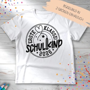 Könnte beinhalten: Weißes T-Shirt mit schwarzem Aufdruck. Der Aufdruck zeigt die Worte "ERSTE KLASSE! SCHULKIND 2026" in einem kreisförmigen Design mit einem Bleistift und einem Herz. Der Text "BÜGELBILD IN 2 GRÖSSEN ERHÄLTLICH" ist ebenfalls sichtbar.