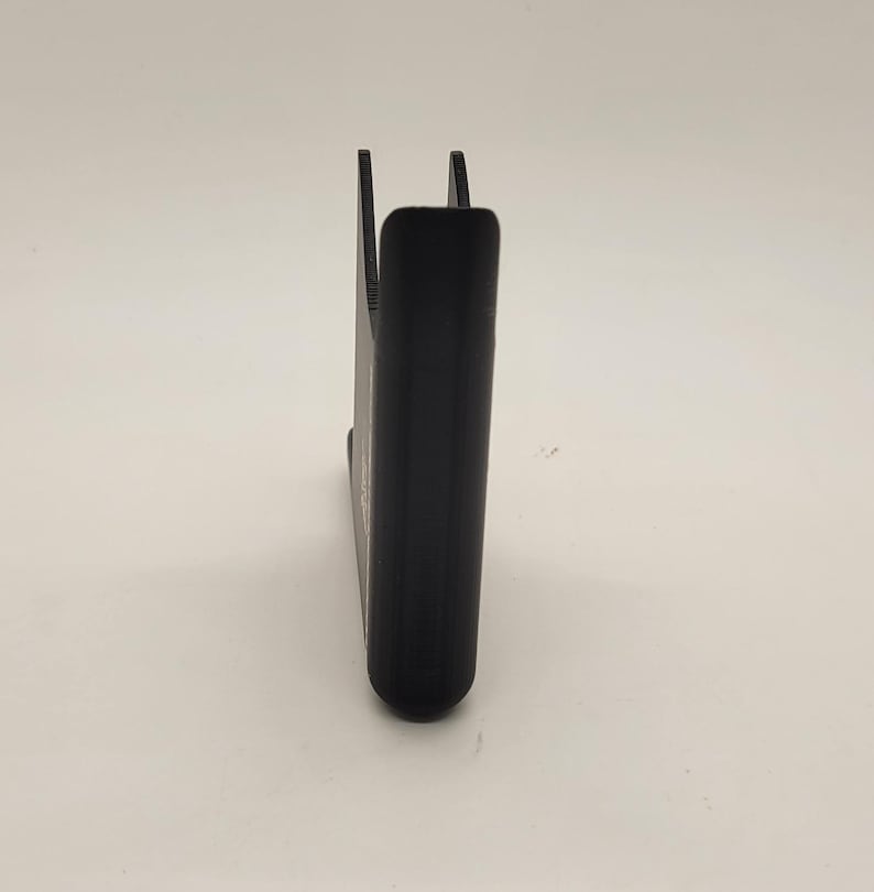 以下が含まれることがあります： 湾曲したデザインの黒いプラスチック製の携帯電話スタンド。スタンドは携帯電話を垂直に保持するように設計されています。