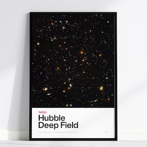 May include: A framed print featuring the Hubble Deep Field image. The artwork displays a vast array of stars and galaxies against a dark background. The print includes the NASA logo and the title "Hubble Deep Field" in white text on a black frame.
