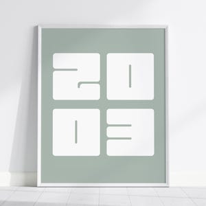 Peut inclure: Une affiche encadrée avec les chiffres "2023" dans un design minimaliste. Les chiffres blancs et carrés se détachent sur un fond vert pâle. L'œuvre est encadrée dans un cadre blanc, parfait pour la décoration intérieure.