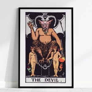 Puede incluir: Impresión enmarcada de una carta del tarot que representa al Diablo. La imagen presenta una figura grande y cornuda con dos figuras más pequeñas encadenadas debajo. La obra de arte está en tonos de naranja, negro y blanco, con el texto "THE DEVIL" en la parte inferior.