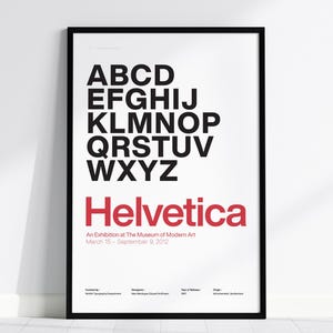 以下が含まれることがあります： 白い背景の額入りポスターには、黒い大文字と赤い「Helvetica」の文字が描かれています。 下には「An Exhibition at The Museum of Modern Art, March 15 - September 9, 2012」と書かれています。