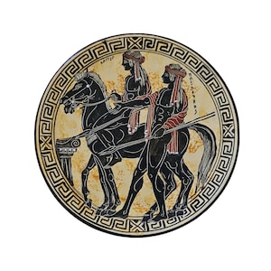 May include: A black and white ceramic plate featuring a Greek design. Two figures on horseback are depicted in black silhouette, with red and yellow accents. The plate has a black and white border with a repeating geometric pattern.