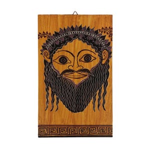 Peut inclure: Plaque rectangulaire en bois avec un visage peint, une longue barbe noire et une couronne de laurier. Le visage a de grands yeux et une moustache. Le fond est brun clair et la bordure présente un motif de clé grecque.
