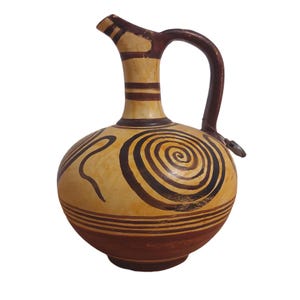 Puede incluir: Jarra de cerámica con cuerpo redondeado, pico y asa. La jarra presenta una base color crema con diseños espirales y lineales marrones. El asa y el pico son de color marrón oscuro. Probablemente sea una pieza decorativa o funcional.