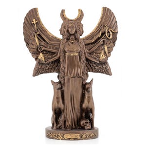 Può includere: Statua color bronzo di una divinità con tre volti, ali e più braccia che tengono vari oggetti. Due cani affiancano la figura, con un teschio alla base. La statua presenta dettagli intricati e una base decorativa.