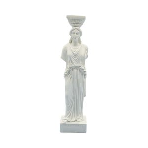 May include: A white Caryatid statue, a sculpted female figure used as a pillar. The statue is standing, wearing a draped gown, and has a bowl-shaped capital on her head. The base of the statue has the word "KARYATIS" inscribed.