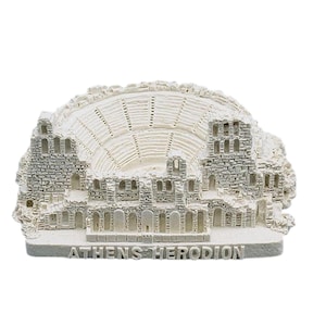 May include: A white and gray miniature replica of the Odeon of Herodes Atticus in Athens. The model features detailed stonework and the text "ATHENS HERODION" at the base. A souvenir or decorative item.