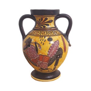 May include: A yellow and black ceramic amphora vase with two handles. The vase features a painted scene of a person reclining and playing a flute. The vase has a dark brown base and rim, and a decorative border.