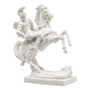 May include: A white marble-style sculpture of a warrior in a crested helmet riding a rearing horse. The warrior holds a sword, and the horse stands on a rocky base. A rectangular plaque on the front of the base features the text MΕΝΑΝΔΡΟΣ Ο ΚΡΗΤΑΣ.