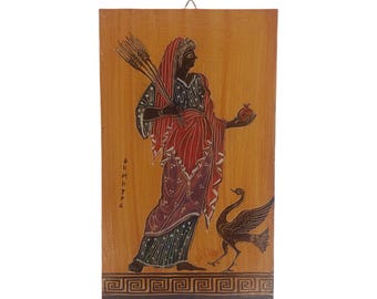 May include: Wooden wall art with a classical Greek illustration. The artwork shows a figure in red and black robes holding wheat and a pomegranate, with a bird. The background is a light brown colour.