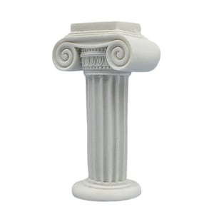 May include: A small, white Ionic column with a detailed capital featuring volutes and a fluted shaft. The base and top are square and circular, respectively. This decorative piece is likely a miniature architectural model.