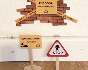 May include: A yellow sign with the text "ELF DOOR UNDER CONSTRUCTION" with an exclamation point.  A brick wall with yellow caution tape.  Two signs on wooden sticks, one yellow with the text "CONSTRUCTION ELVES ONLY" and an exclamation point, and one red triangle with the text "STOP" and a cartoon elf.
