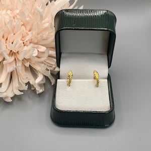 May include: A pair of gold snake hoop earrings in a green velvet jewellery box.