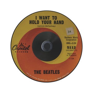 May include: A vintage vinyl record for the Beatles' song "I Want to Hold Your Hand." The record features a yellow and orange design with the Capitol Records logo. The label includes song details, the band's name, and other information.