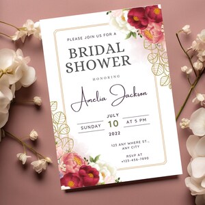 Könnte beinhalten: Eine weiße Einladung zu einer Brautparty mit goldenen Akzenten und floralen Illustrationen. Die Einladung lautet: "Bitte nehmen Sie an einer Brautparty zu Ehren von Amelia Jackson teil, Sonntag, 10. Juli 2022 um 17:00 Uhr, 123 Any Where St., Any City, RSVP unter +123-456-7890."