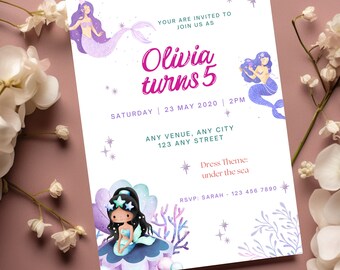 May include: A white invitation card with purple and blue illustrations of mermaids. The text reads "Olivia turns 5" with the date and time of the event. The dress theme is "under the sea".
