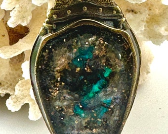 May include: A bronze pendant with a teardrop-shaped resin inlay. The resin is a deep green color with flecks of gold and silver.