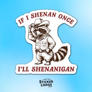 Puede incluir: Una pegatina con un mapache de dibujos animados vestido con un atuendo de vaquero, con sombrero y camisa. El texto granate dice "If I Shenan Once I'll Shenanigan". El logotipo de Sticker Lodge está en la parte inferior, todo sobre un fondo azul.