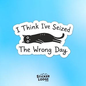 May include: A white sticker with the text "I Think I've Seized The Wrong Day" and a black cat illustration. The cat is lying down with its eyes open. The sticker has a blue background.