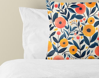 Puede incluir: Un cojín cuadrado con fondo color crema y un patrón repetitivo de hojas y tallos azul oscuro, intercalados con flores circulares y pequeños brotes en tonos vibrantes de naranja, amarillo y coral.