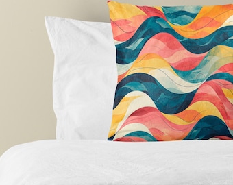 Puede incluir: Un cojín cuadrado con un patrón repetitivo de líneas onduladas horizontales en tonos azul verdoso oscuro, naranja vibrante, rosa suave y crema. El cojín está colocado frente a una almohada blanca y una sábana blanca.
