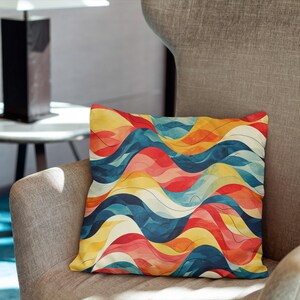 May include: A square throw pillow featuring a repeating pattern of horizontal wavy lines in shades of red, orange, yellow, and blue. The design consists of overlapping, fluid curves that create a sense of movement across the entire surface of the pillow.