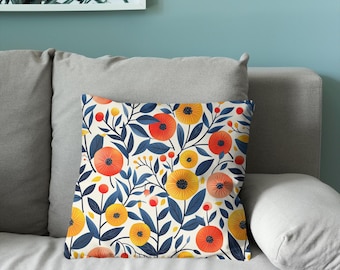 Puede incluir: Un cojín cuadrado con un patrón botánico repetitivo de flores naranjas y amarillas vibrantes con hojas y tallos de color azul oscuro sobre un fondo color crema. El diseño incluye pequeños capullos redondos y ramas delgadas.
