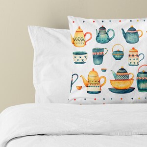 May include: A square throw pillow featuring a white background with a repeating watercolor pattern of various teapots, cups, and bowls in shades of blue, yellow, and orange, accented by a border of small colorful polka dots.