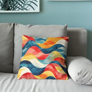 May include: A square throw pillow featuring a vibrant, abstract pattern of flowing, undulating waves in shades of deep blue, bright yellow, and warm red, accented with thin, dark lines that follow the curves of the colorful design.