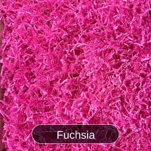 May include: A close-up of fuchsia-colored shredded paper, commonly used for packing and gift wrapping.