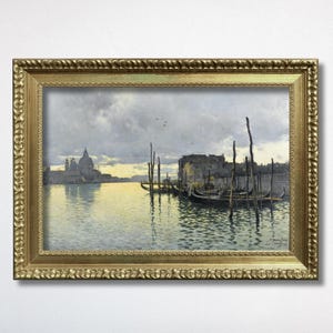 May include: A framed oil painting depicting a Venetian canal scene at dusk. The artwork features gondolas moored near wooden pilings, with a distant domed cathedral silhouette against a pale yellow and grey sky, all encased in an ornate gold frame.