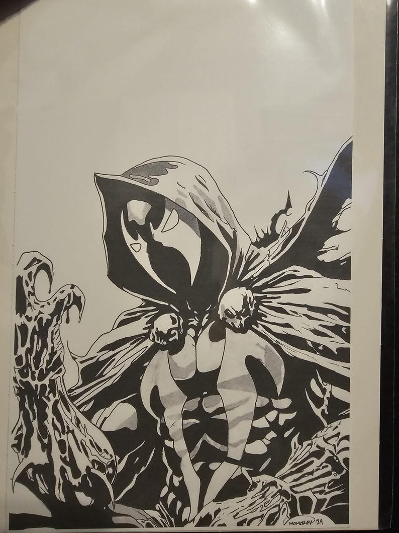 Op de afbeelding: Een zwart-witte inktillustratie van een figuur met een kap en masker, gekleed in een cape vastgemaakt met twee schedelvormige sluitingen. De figuur heeft &eacute;&eacute;n klauwhand naar voren uitgestoken. De handtekening Momoko '24 staat rechtsonder.