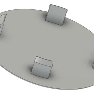 May include: A gray metal plate with three raised, curved tabs on the edge. The plate is round and has a smooth surface.